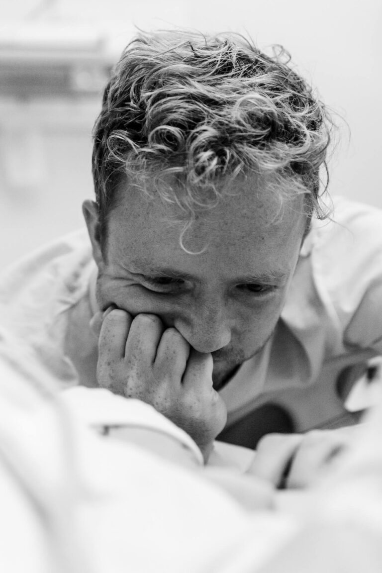 Nieuwe vader stralend kind bekijken na bevalling bij moeder op de borst foto door geboortefotograaf
